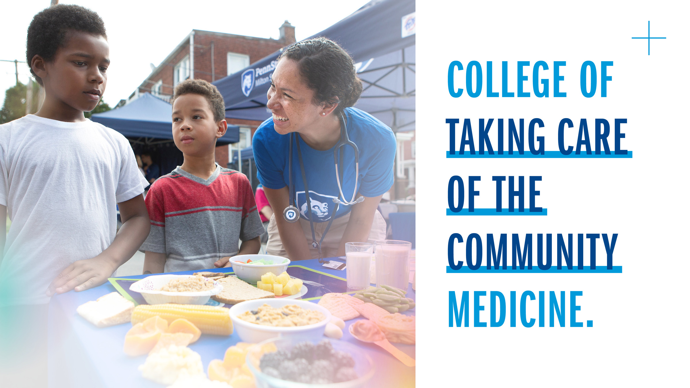 College of Taking Care of the Community Medicine with college staff member looking at a young boy smiling, another boy is between them and a table of food in front.